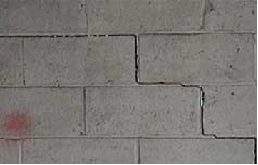 A cinder block wall with a crack around several blocks